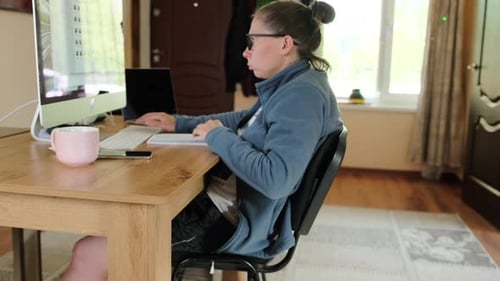 Woman works in cozy home environment in front of computer monitor typing away on keyboard