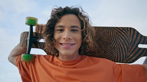 Happy Cheerful Guy Smiling to Camera Holding Skateboard on Shoulders Close Up