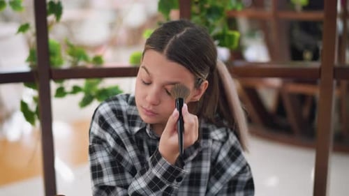 Closeup View of Young Girl Applying Makeup on Left Cheek Using Brush