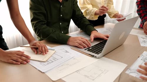 Architect compare writing detail of blueprint with plan in laptop. Delineation.