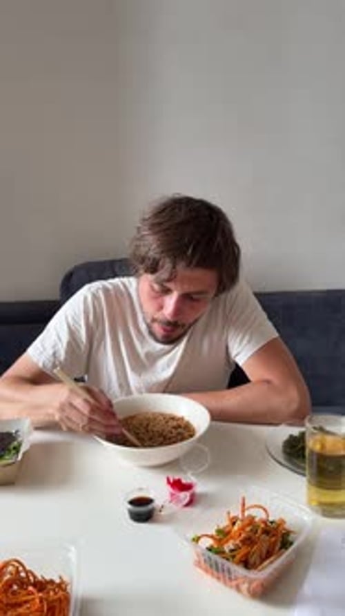 Man Enjoying Takeout Noodles at Indoor Table