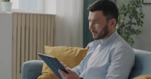Man Relaxing at Home Using Tablet