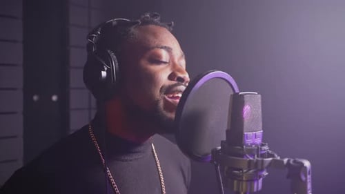 Music Production Studio Adult Black Guy in Headphones Singing Song to Microphone