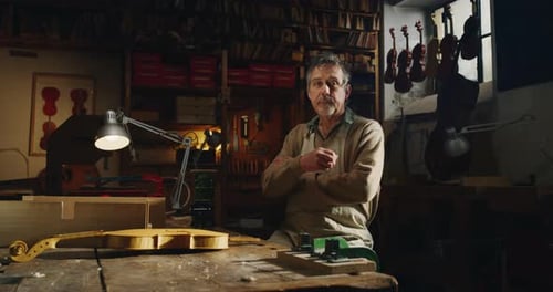 Cinemática de un maestro luthier artesano profesional que sonríe satisfecho con su trabajo ante la cámara