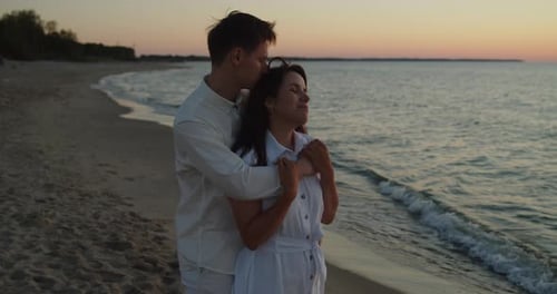 Man and Woman Standing on the Beach in Front of the Sea Embracing