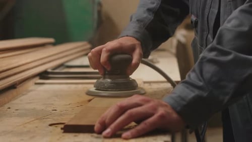 Joiner Polishing Wooden Planks in Workshop