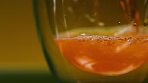 Close up of a fresh orange juice being poured into a glass