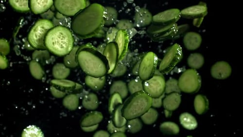 Cucumber Slices Suspended in Air on Black Backdrop