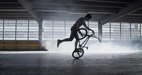 Young Adult Performs BMX Tricks Indoors