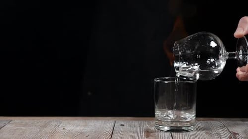 Clear Liquid Pouring Into a Short Glass