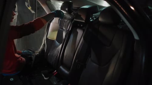 Cleaning Worker Sprays and Cleans Car Interior