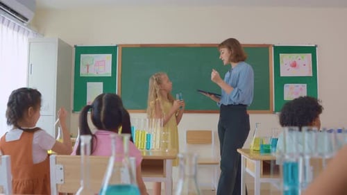 Adorable student learn with teacher in classroom at elementary school.