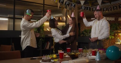 Homens felizes em roupas de negócios levantam seus óculos e tilintam durante uma festa corporativa no