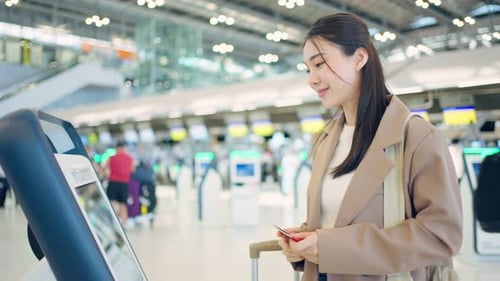 Passageira asiática faz o check-in no balcão do terminal do aeroporto para viajar de avião para o exterior.