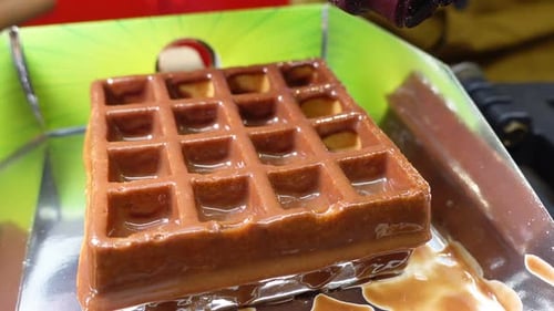 Chocolate Sauce Being Poured on a Waffle