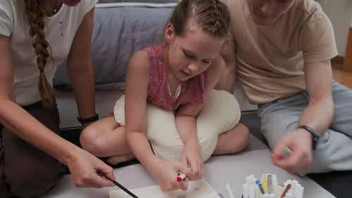 Parents and Daughter Drawing Together on Paper at Home