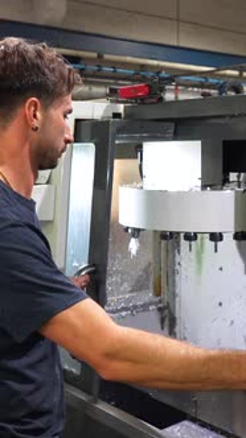 Man Overseeing Automated Metal Milling Machine in Factory
