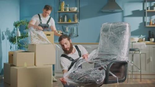 Workers of Moving Company With Uniforms Carefully Unpacking Things at Boxes