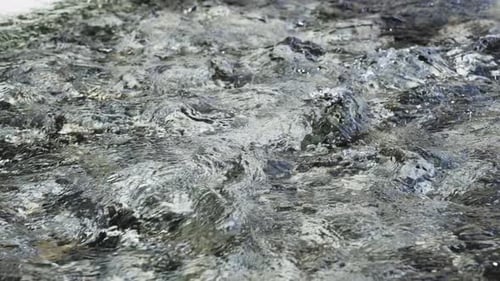 Imagine a Picturesque Scene of Clear Water Cascading Over Rocks Set in a Lush Natural Setting That