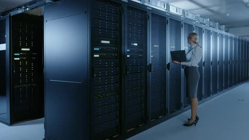 Dans un centre de données : une technicienne informatique exécute un programme de maintenance sur un ordinateur portable et contrôle les opérations