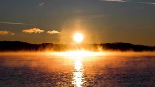 Sonnenaufgang über ruhigem Meer. Morgendämmerung über dem Horizont, Meer, Wasser. Orangefarbener bewölkter Himmel. Sonnenpfad auf dem Wasser