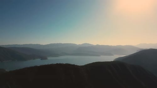 Aerial drone flying over a lake, water dam, with mountains at sunrise. Beautifull dreamy landscape.