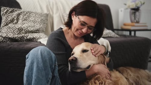 Woman Petting Golden Retriever Dog on Living Room Floor