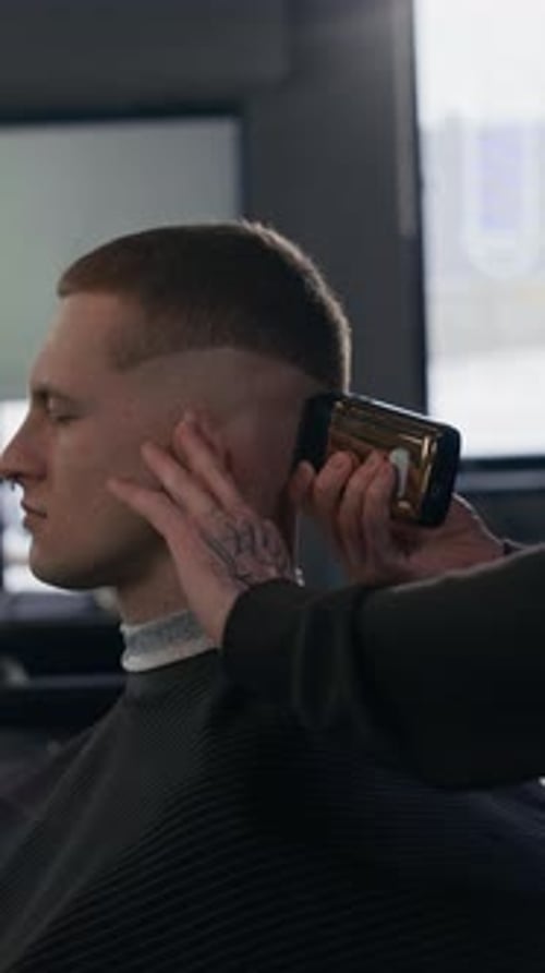Unbekannter Friseur, der die Schläfen und den Hinterkopf des Kunden beschneidet