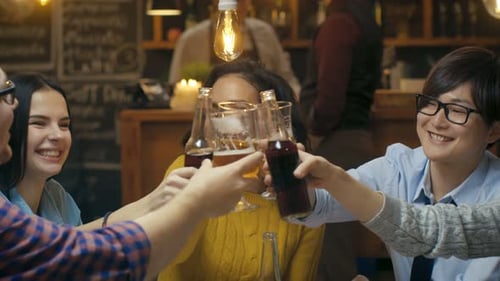 Friends toasting drinks at a table in bar