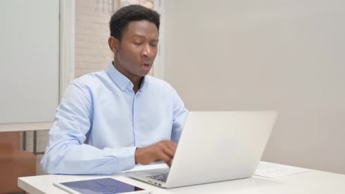 Coughing African Businessman Using Laptop in Office
