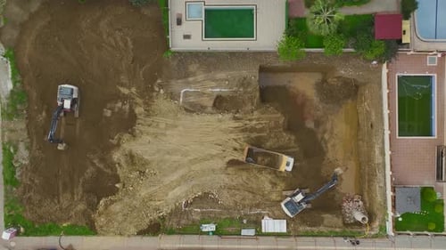 Aerial Video Aerial Footage of an Active Construction Zone with an Excavator Digging and a Truck