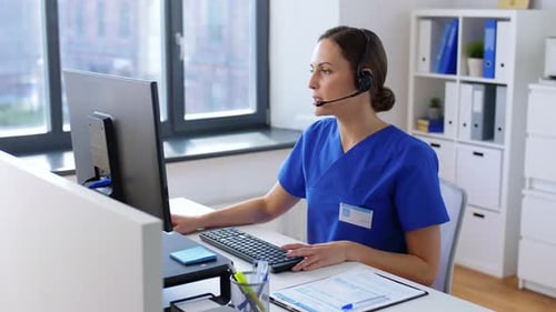 Hispanic doctor with headset typing at computer in hospital telemedicine office