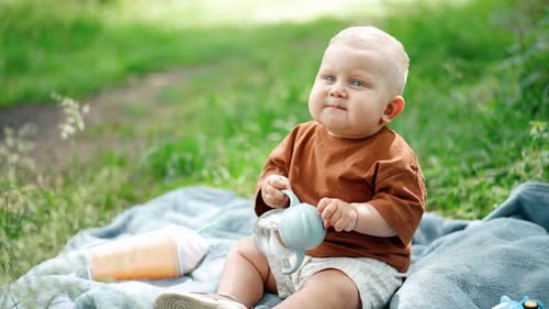 Smiling Baby with Bottle Sitting Outdoors