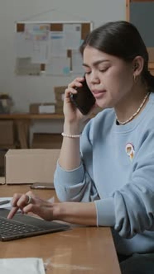 Young Woman Works on Laptop and Talks on Phone