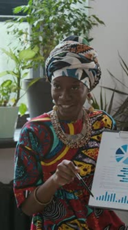 Black Woman Discussing Charts and Graphs with Colleague in Sustainable Office
