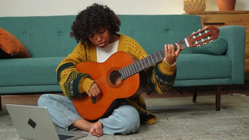 Young Adult Plays Guitar in Home Setting