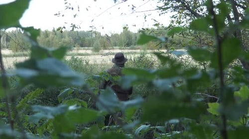 Hunter hiding in green grass and foliage, Cinematic slow motion with shallow depth of field