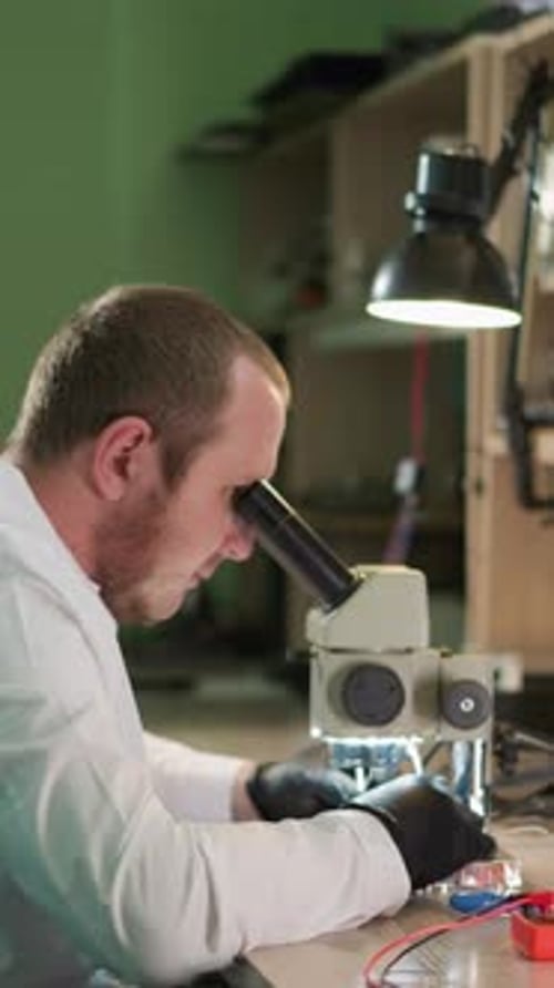 Scientist Looking Into Microscope in Lab