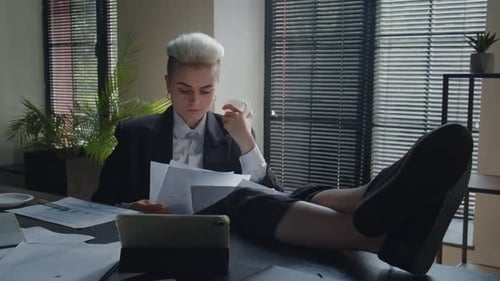 Professional Woman Relaxes at Desk with Paperwork