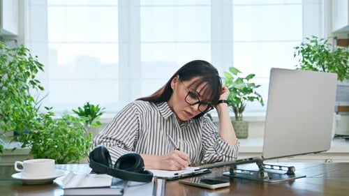 Middleaged Serious Woman Working at Computer Laptop in Home Office