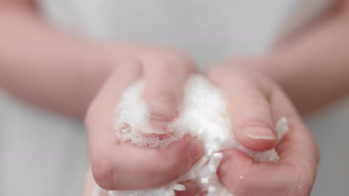 Hands Squeezing a Bath Sponge to Create Bubbles