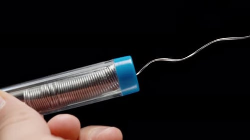 Man's Hands Close-Up Pulling Tin Solder Coiled in Spiral for Soldering Iron from Small Container.