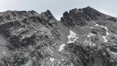 Une vue aérienne s'élève sur une roche de montagne monochrome déchiquetée vers le sommet