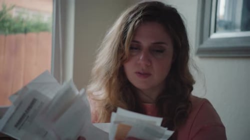 Stressed out Woman in Her Kitchen Organizing Receipts and Bills, Throws them in the Air, Overwhelmed