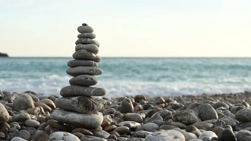 Pirámide de roca equilibrada en una playa de guijarros contra las olas del mar