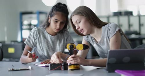 High school students working on a robotic arm in class