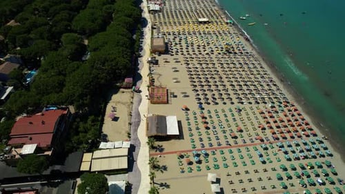 Large beach on the Durres coast, Albania, with green pines, white sand, turquoise sea water, and hot