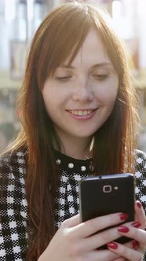 Smiling Woman Using Mobile Phone in City