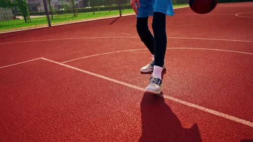 a Tall guy basketball player with the ball shows his dribbling skills during practice on the court