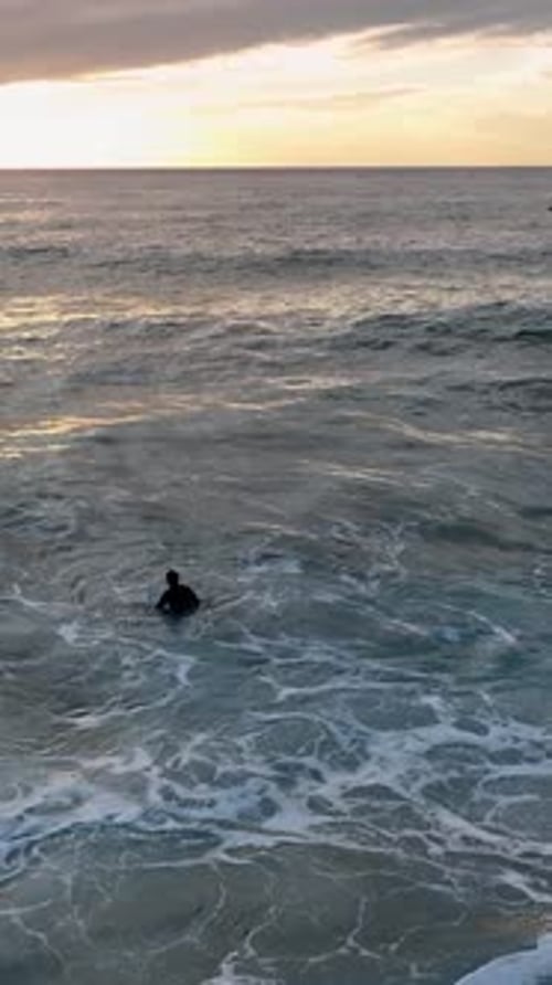 Vertical Video Mesmerizing Aerial Capture Surfers Conquering Waves at the Azure Sea Beach and Cloudy